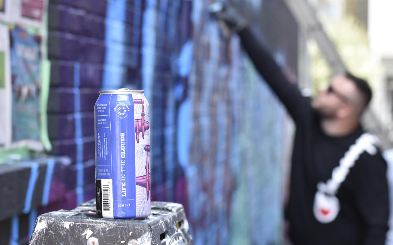 Can of Collective Arts Brewing's double dry hopped beer with graffiti artist in the background
