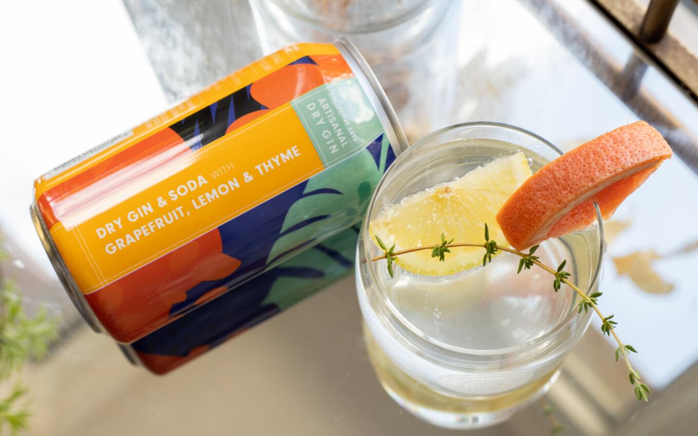 Can of Collective Arts Brewing's artisanal dry gin next to a glass filled with it and lemon and orange garnishes