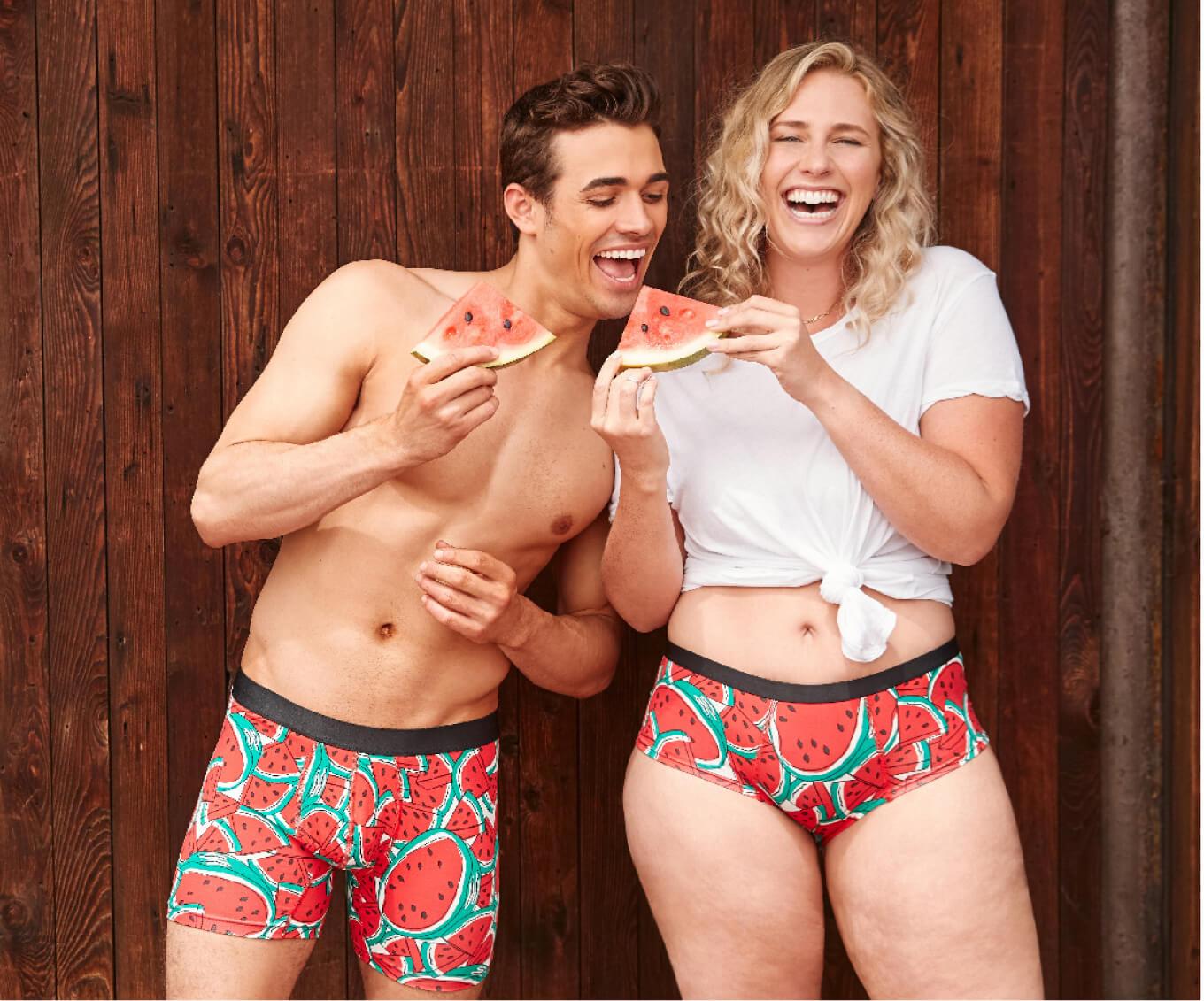 A man and woman wearing MeUndies underwear in a watermelon pattern, both posing with watermelon slices and laughing